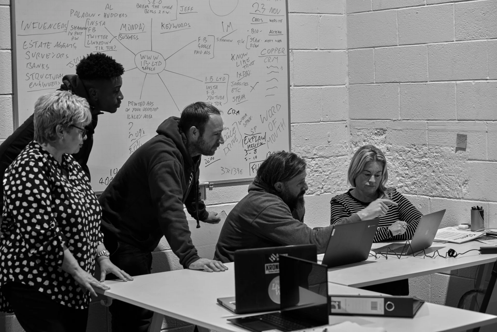 Team collaborating in meeting room with whiteboard.